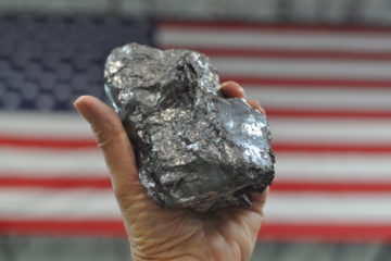Graphite being held inside Urbix plant with American flag in background.